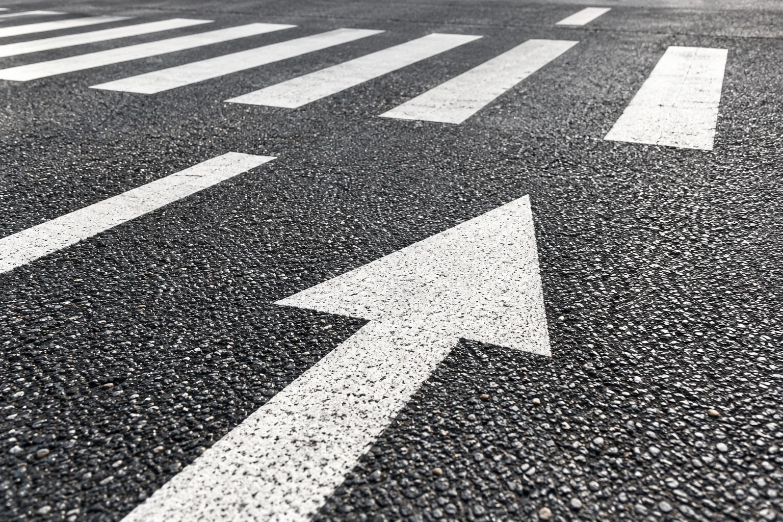 Illustrative white directional arrow and crossing markings on asphalt